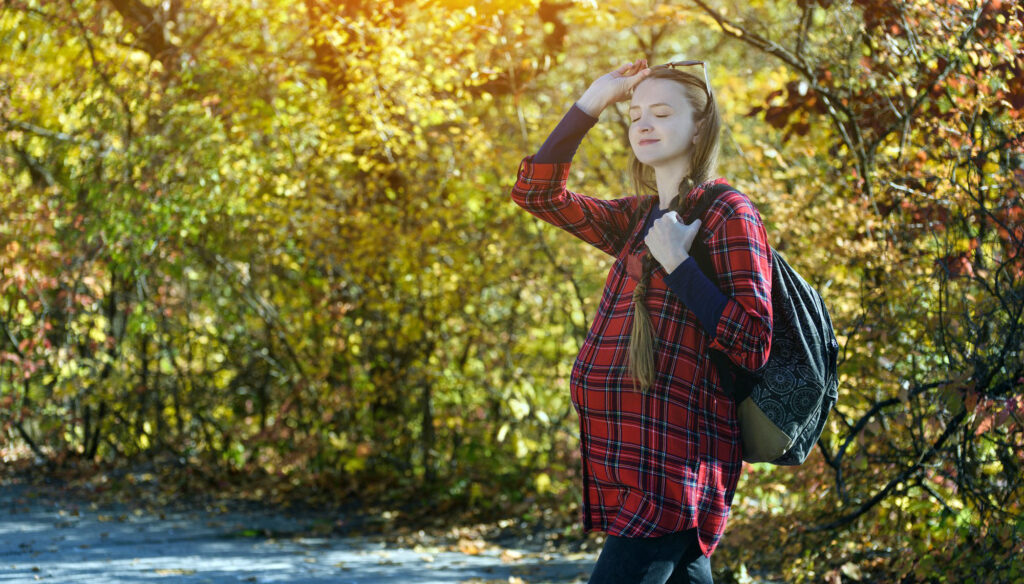 Young pregnant woman in the autumn forest while hiking